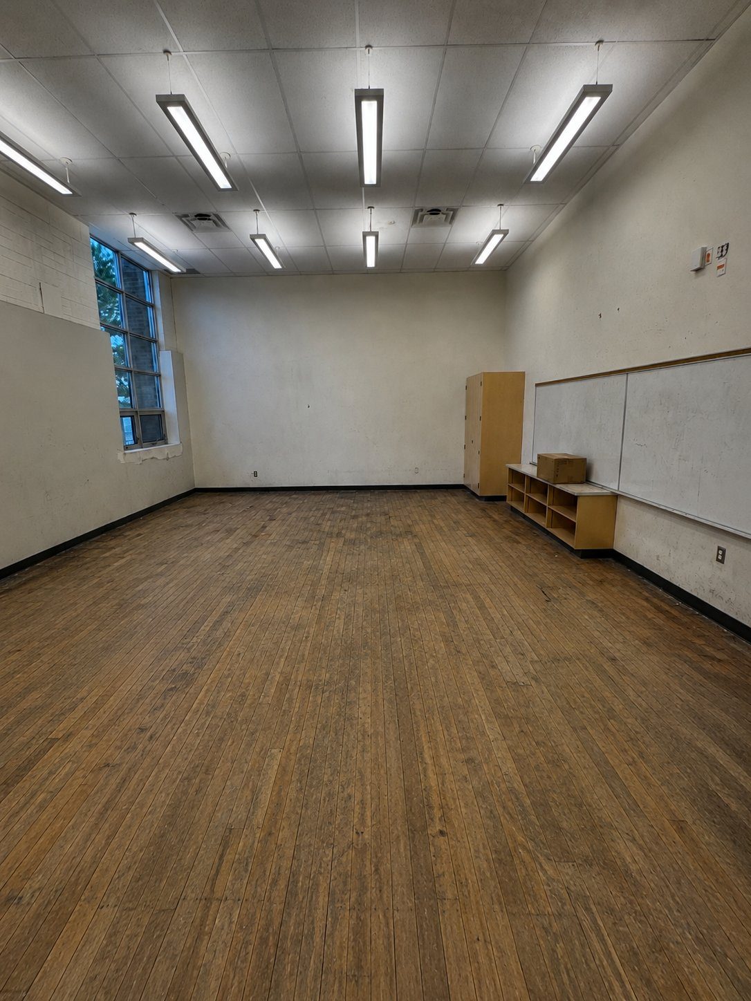 Classroom with worn, faded hardwood flooring before replacement
