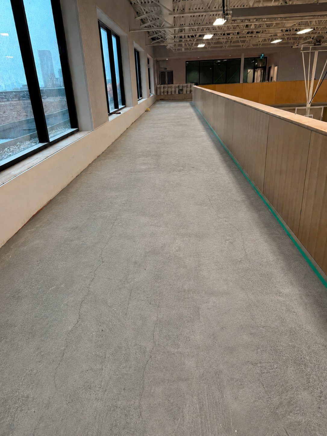 Mezzanine walkway with bare cracked concrete before resurfacing
